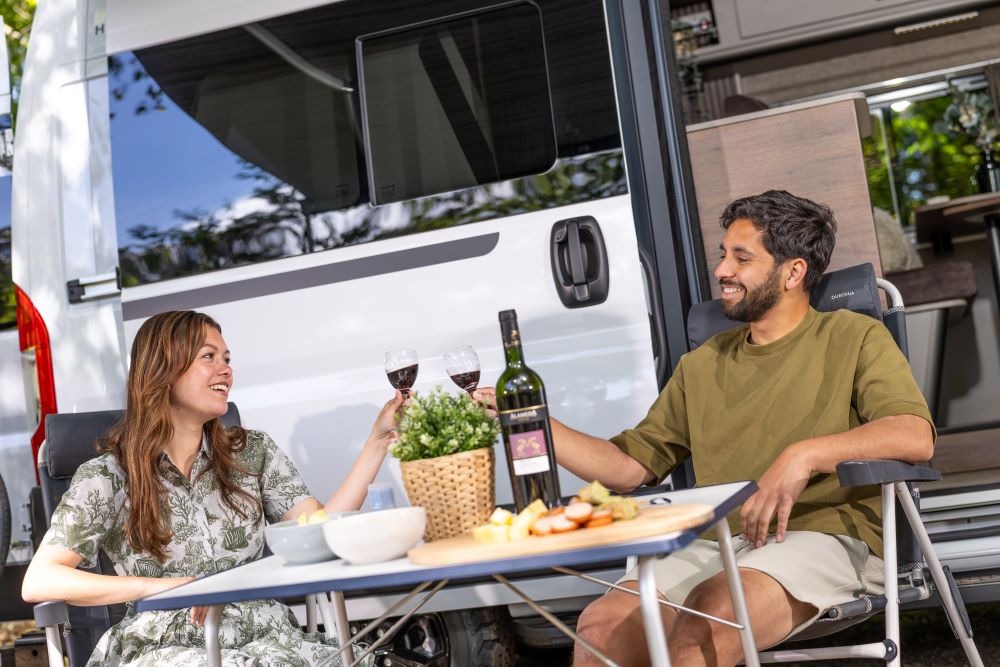 Twee mensen die zitten voor een Hooglander campervan van Aart Camperinbouw